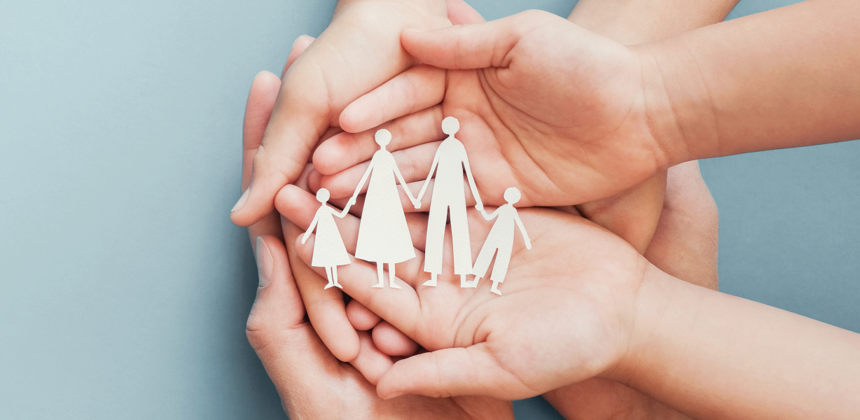 A family made out of paper cutouts being held in the palms of several people