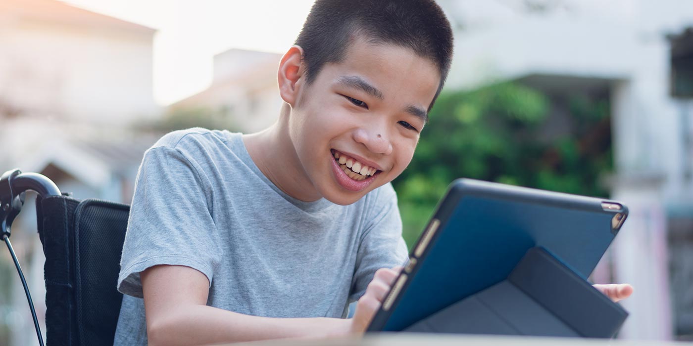 Boy sitting in a wheelchair using a tablet Boy sitting in a wheelchair using a tablet