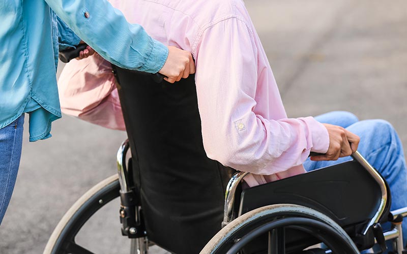 Child in their wheelchair being pushed by their carer
